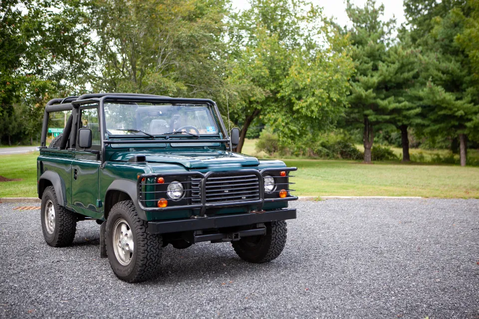 Green Land Rover Defender parked on a gravel drive