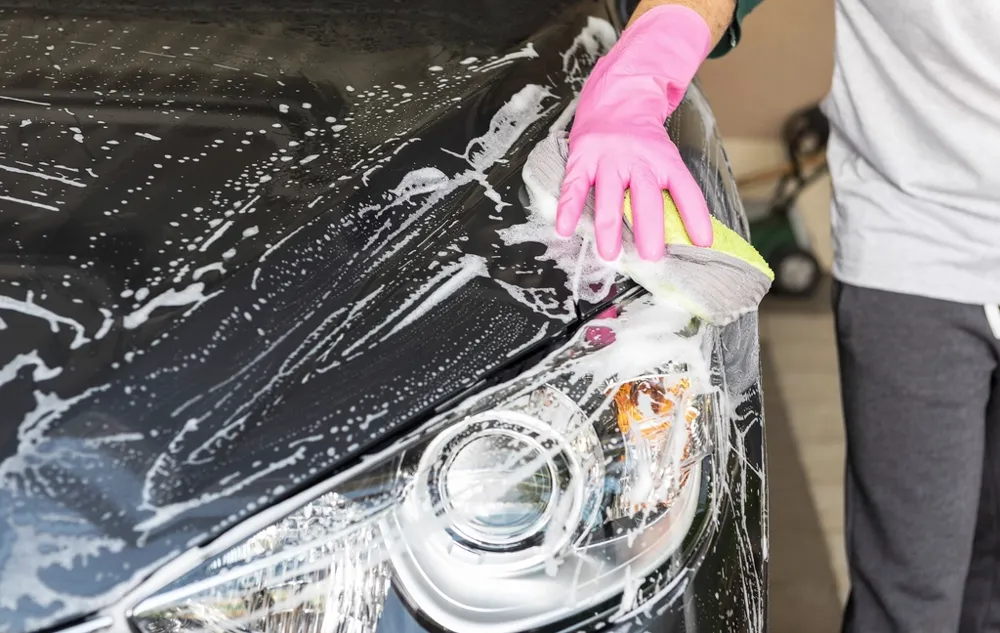 Detailer washing a car by hand with a soapy mitt